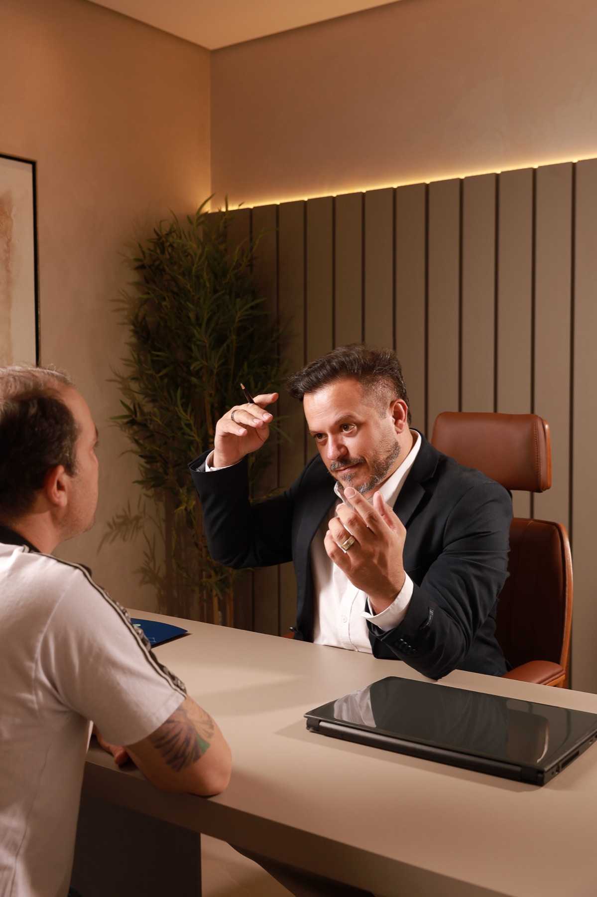 Dr. Rodrigo Redondo em consulta, apontando para a linha frontal do paciente no consultório